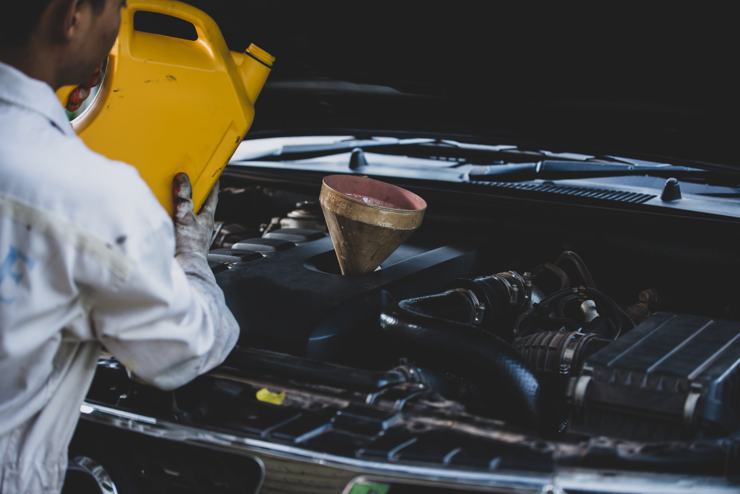 close up auto mechanic hand pouring and replacing fresh oil into